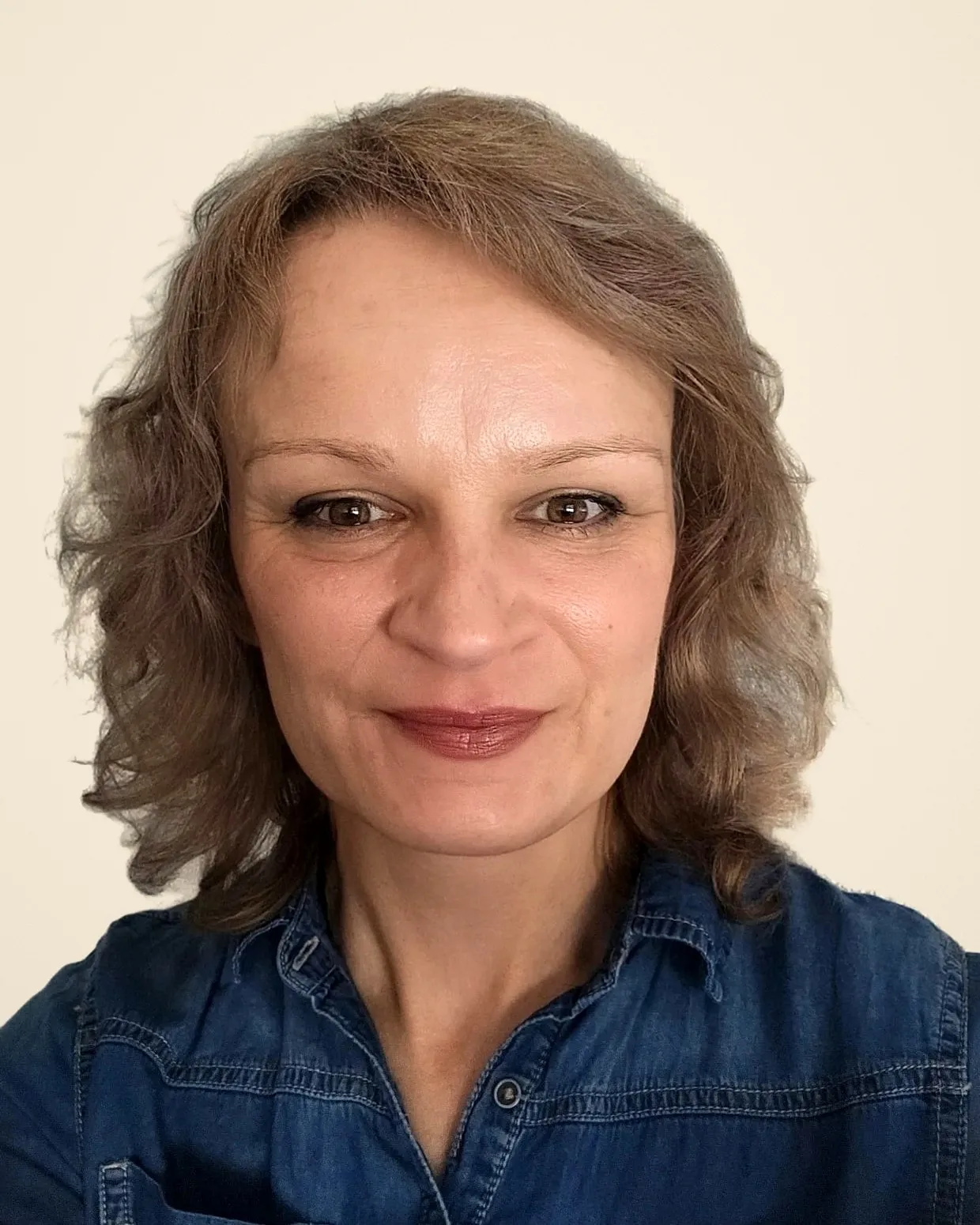 Dorota, lockige schulterlange Haare, Jeanshemd, lächelt in die Kamera